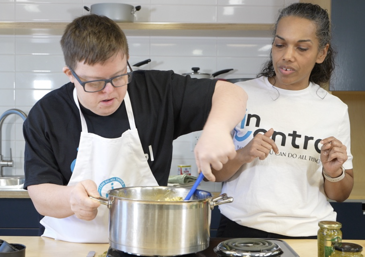 A client stirring a mixture in a pan with a coach standing next to him